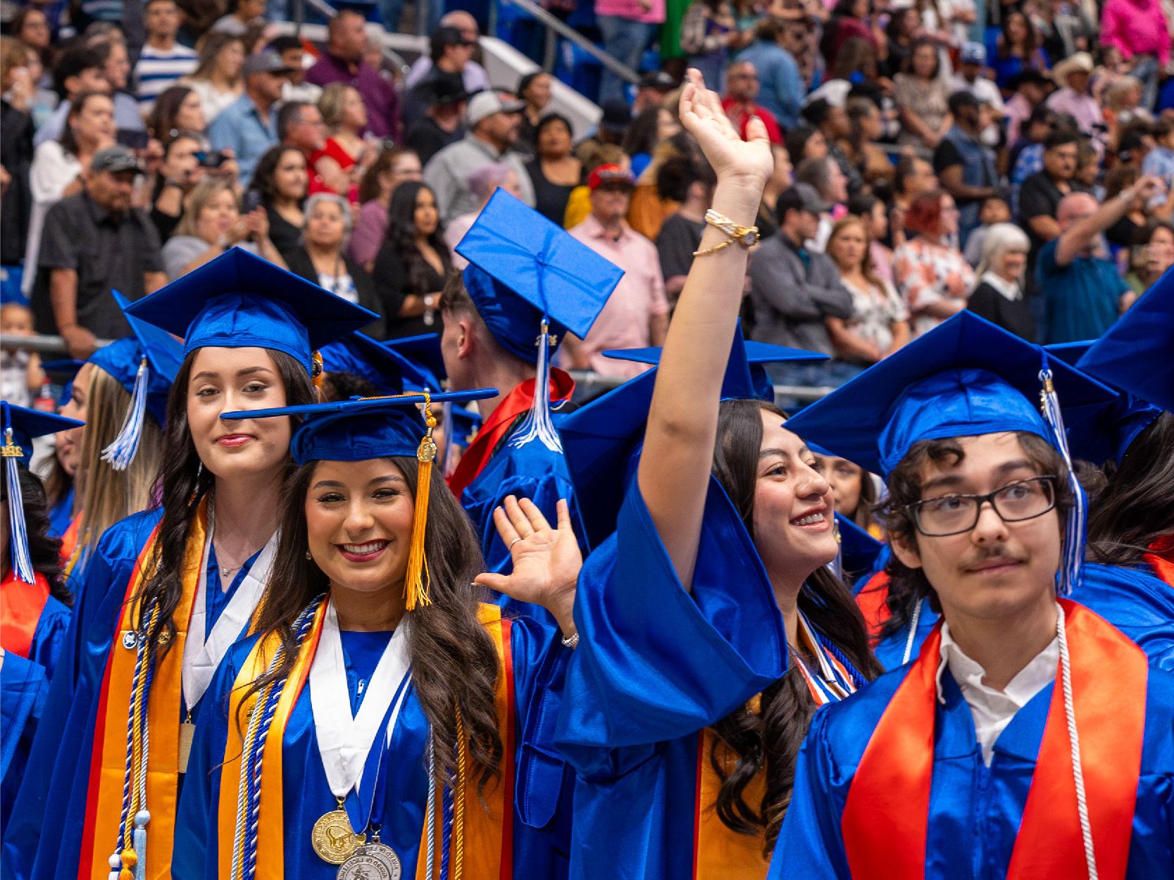 Graduates in Blue Caps and Gowns Waving and Smiling